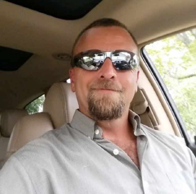 A selfie of a white gentleman with sunglasses and a button up shirt.
