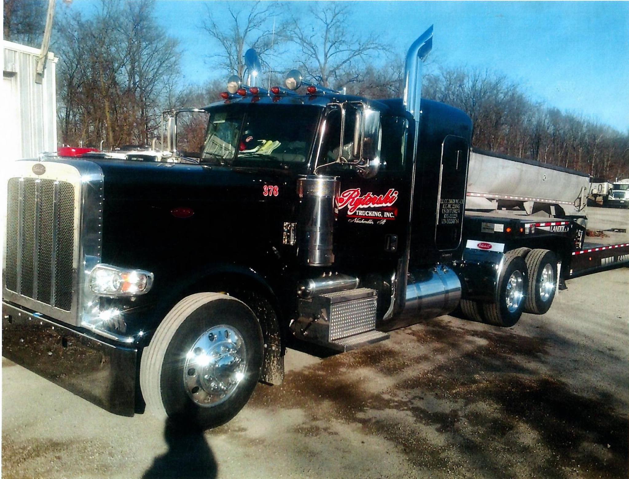 A large, black semi with a red Ryterski Trucking Inc. logo on the door. 